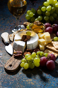 小吃 葡萄酒和卡门培尔奶酪在黑暗的背景下，垂直