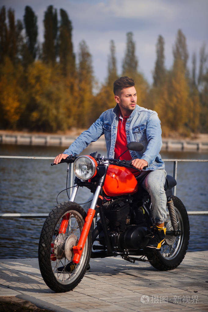 年轻的体育时尚男子骑摩托车, 一个温暖的镜头, 深秋