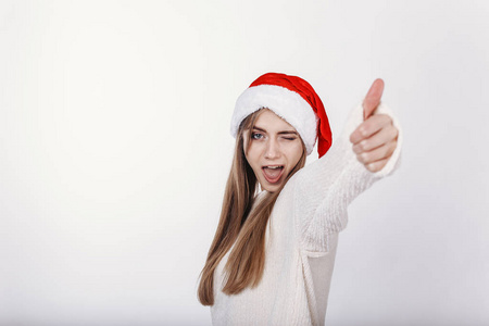 戴圣诞帽的女人竖起大拇指。 模特看着相机眨眼。