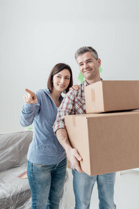 一对夫妇搬进了一所新房子，女人指着她，男人拿着纸板箱