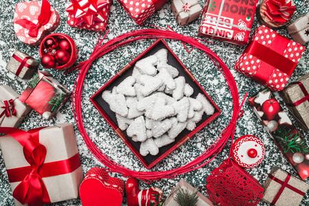 红色圆圈从装饰魔杖打开黑色圣诞礼物盒包装和饼干饼干在灰色石头大理石背景贺卡。