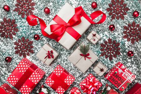 从上面的顶部平视圣诞礼物盒和红色球体包装装饰手工雪花在灰色石头大理石背景圣诞贺卡。