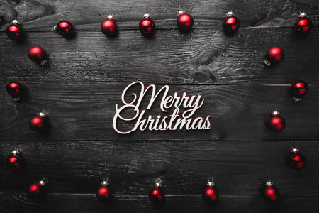 黑色的木制背景，红色的球体和快乐的圣诞标志，从上面的贺卡上可以看到文字。