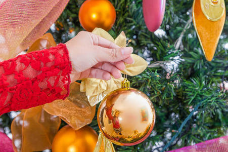关闭妇女手拿着一个圣诞球装饰圣诞树, 快乐的圣诞桅杆和快乐的新年概念