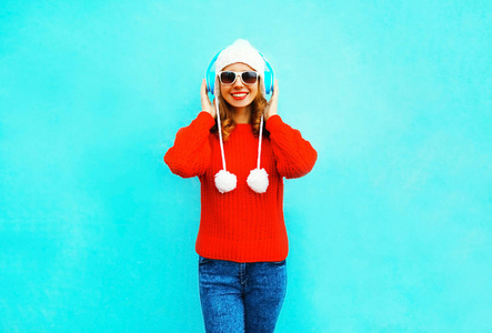 穿着红色毛衣的快乐微笑的女人, 在无线听音乐