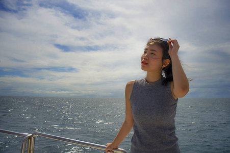 年轻的迷人和快乐的亚洲华人女子乘船或渡轮享受海风在夏季假期乘船旅行