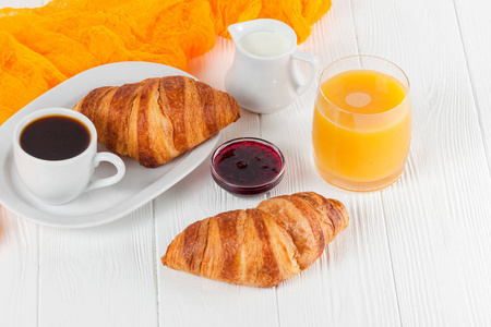 新鲜出炉的牛角包橙汁, 果酱, 黑咖啡在白色的木制背景。法式早餐早上的新鲜点心美味的甜点特写摄影。水平横幅