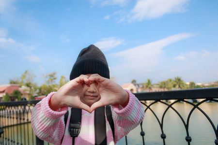 亚洲小女孩显示手使心脏形状与幸福