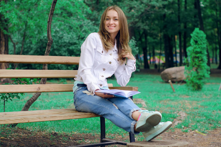 美丽的年轻女子在自然长凳上看书