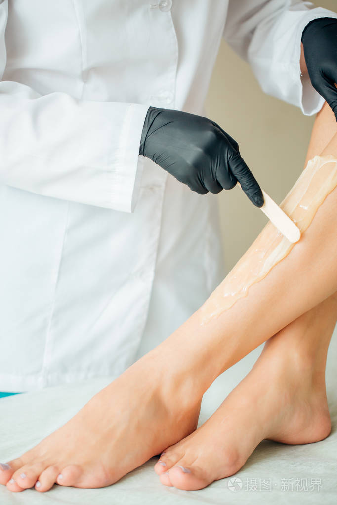 在spa 中心关闭美容师打蜡女性腿