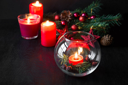 在黑暗的木制背景上燃烧蜡烛和圣诞装饰。 节日的气氛。 低键