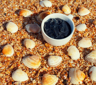 海滩上一个带贝壳的杯子里的水疗用死海泥