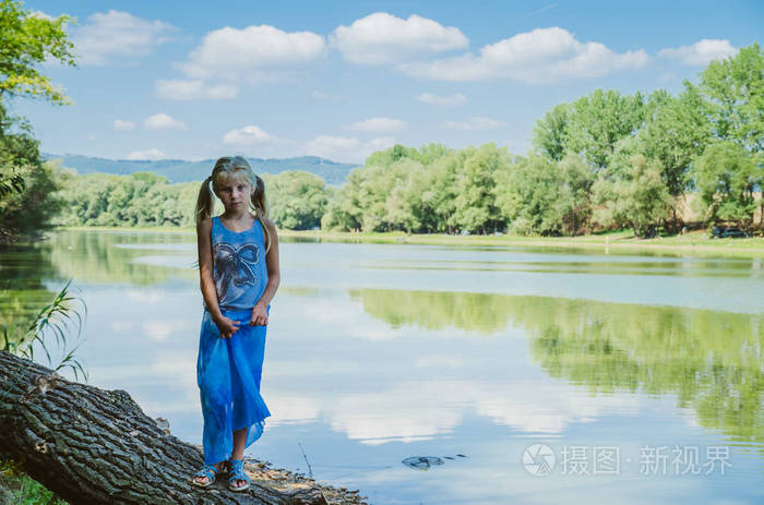 小女孩走在河岸边的树枝下