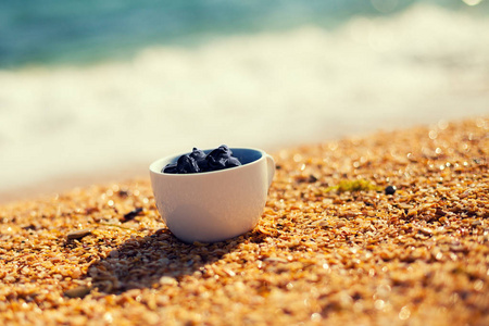 海滩上一个杯子里的水疗用死海泥