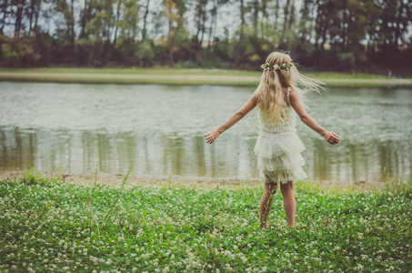 一个金发碧眼的小女孩，晚上在河边的绿草中跳舞