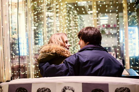 生活方式肖像的情侣相爱在城市的街道上，有很多灯光的背景。 新年和圣诞节庆祝概念。