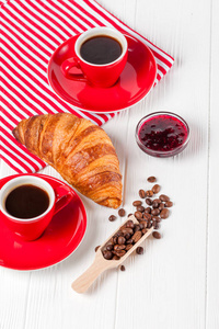 餐巾上刚出炉的羊角面包, 白色木制背景的红杯咖啡。法式早餐早餐的新鲜糕点。美味的甜点特写摄影。垂直横幅