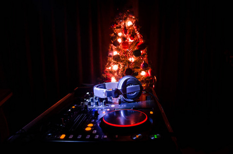 Dj 混合器与耳机在黑暗的夜总会背景与圣诞树新年前夕。在 Dj 桌上关闭新年元素或符号 圣诞老人雪人狗2018礼品盒 