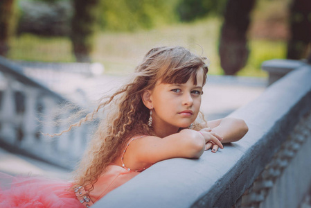 在阳光明媚的日子里,穿着漂亮桃色裙的小白种人女孩在公园里摆姿势