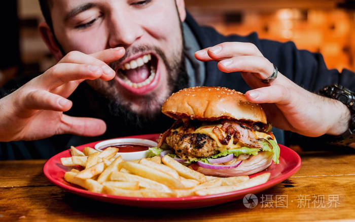年轻人在餐馆吃芝士汉堡
