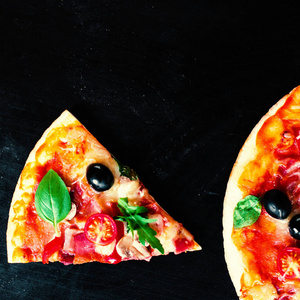 火腿番茄和奶酪比萨饼在黑暗的背景。 热比萨饼和意大利香肠香肠在披萨店或餐厅供应
