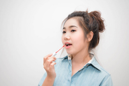 美丽的亚洲年轻妇女做化妆用唇彩