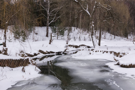 冰雪覆盖的冰冻河流冬季森林景观。
