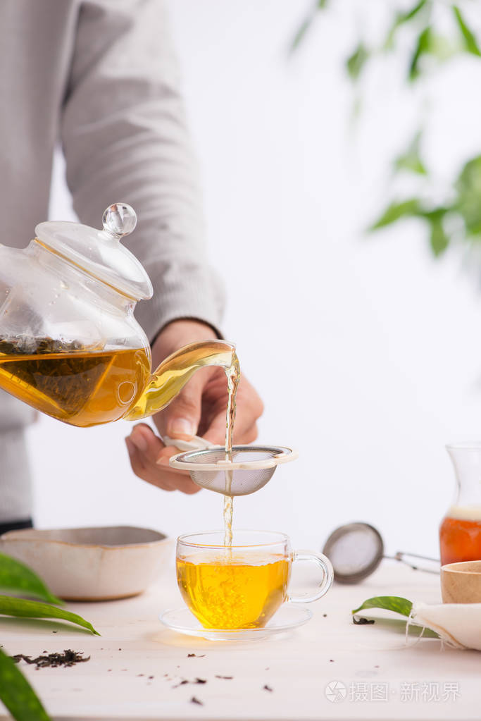 从一个茶壶里倒出一杯茶在一张木桌上