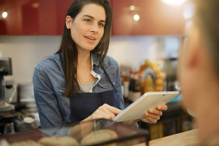 咖啡店的女服务员在订购数码平板电脑