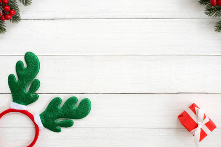 圣诞节背景。圣诞框架由冷杉叶，冬青浆果，圣诞头巾，和红色礼品盒白色木材背景。创意平躺，顶层设计
