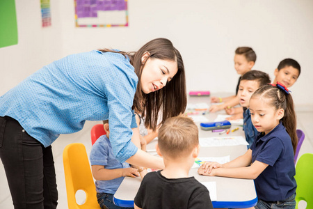 可爱的女幼儿教师在教室里耐心地向她的一个学生解释他的工作安排