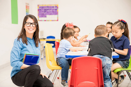 漂亮的黑发女孩教幼儿园给一群学生，看上去很高兴