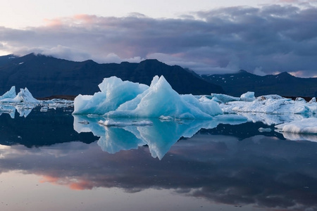 壮观的日落与融化的冰山绿宝石蓝色在 Jokulsarlon 冰川泻湖基地