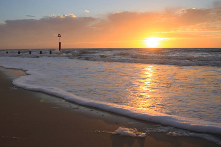 清晨黎明日出橙色的天空，太阳升起在地平线上。 轻柔的海浪拍打着沙滩。