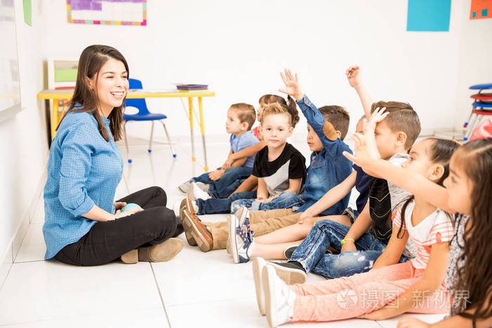 美丽的幼儿教师和她的一群学生举手,在学校玩得很开心