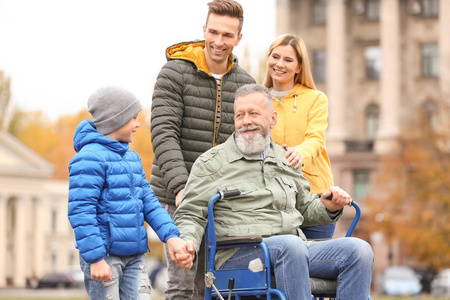 老人在轮椅与他的家庭在户外在秋天天