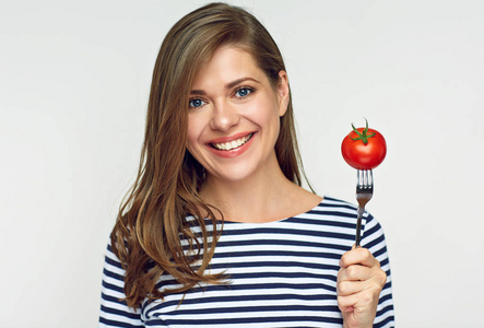 微笑的少妇拿着蕃茄在叉子