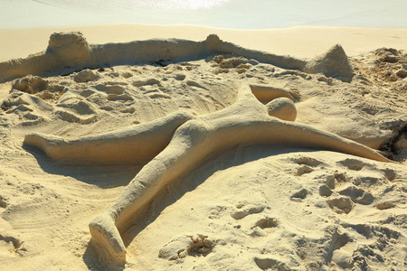 可爱的沙雕，代表一个人躺在海滩上，脸朝下。 阿鲁巴岛。 加勒比海。 范妮的背景。