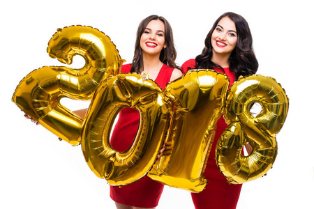 两个欢快的女孩在红色礼服摆在白色背景的金色数字气球的肖像, 新的2018年