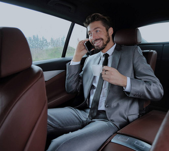 快乐年轻的商人，在汽车的后座中使用手机