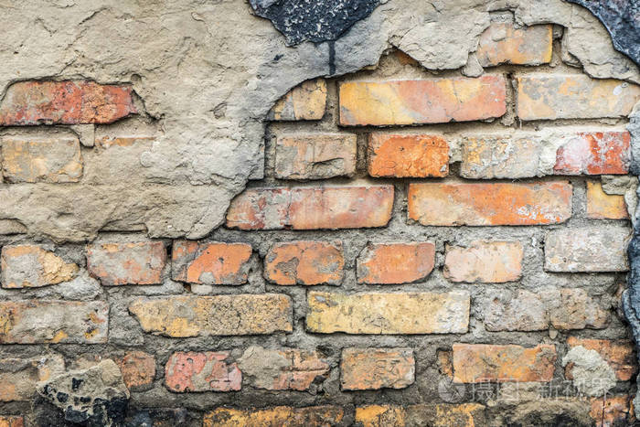 房子的旧墙在松散的石膏下暴露砖墙