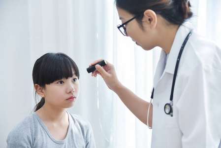 医生戴眼镜检查一个小女孩的病人的眼睛