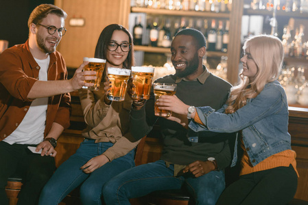 快乐的多文化朋友一起在酒吧喝啤酒