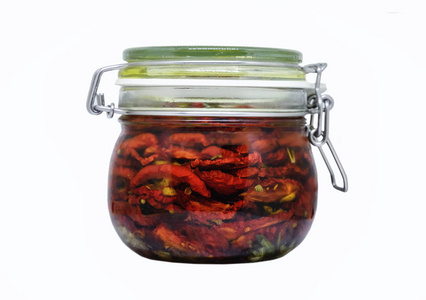 晒干的西红柿在一个罐子与橄榄油和草药隔离