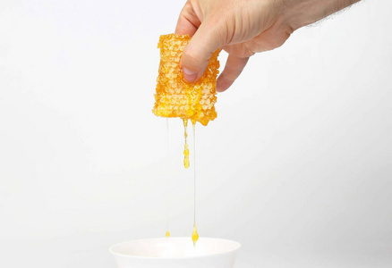 滴着手指在白色背景上的蜂窝照片