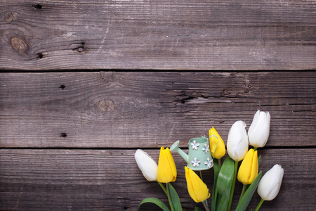 春天，黄色和白色郁金香，花和装饰浇水罐在老式的木制背景。 选择性聚焦。 文本的地方。