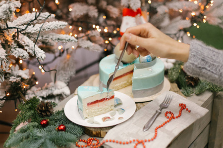 圣诞蛋糕与果冻和蛋奶酥与女性手和冷杉灯和圣诞节装饰的背景。