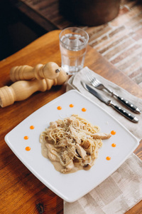 传统的意大利面食碳原在白色盘子上，餐巾纸和胡椒研磨机上有角质。
