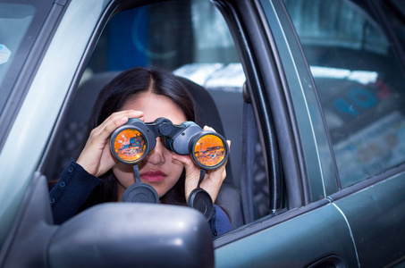 年轻的女人用她的车内黑色双筒望远镜跟踪