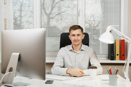 严重和全神贯注的商人在办公桌前的衬衫, 工作在电脑与现代显示器